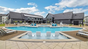 En swimmingpool med solstolar och en byggnad med modern design.