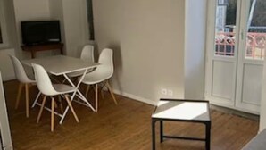 Una sala moderna con comedor, un televisor de pantalla plana y un amplio ventanal con vistas a árboles.