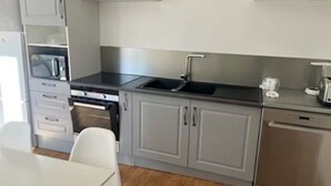 Una cocina moderna con armarios grises, lavavajillas de acero inoxidable y encimera negra.