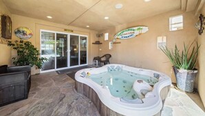 Ein Innenhof mit Whirlpool, Steinböden und einer Glasdoor, die nach draußen führt.
