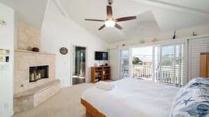 Ein Schlafzimmer mit einem großen Bett, einem Kamin, einem Deckenventilator und Blick ins Freie.