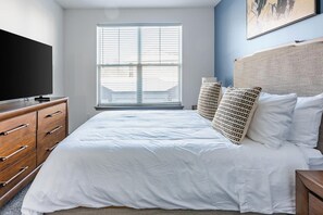 A bedroom with a bed, wooden dresser, and a television. - Landing | Stunning 1BD, Courtyard, Gym (Enlow)