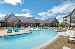 A swimming pool with lounge chairs and a building with a dark facade. - Landing | Stunning 1BD, Courtyard, Gym (Enlow)