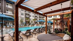 A poolside area with lounge chairs, umbrellas, and a wooden pergola. - Landing | Spectacular 2BD, Yoga Studio, Pool (St. Augustine)