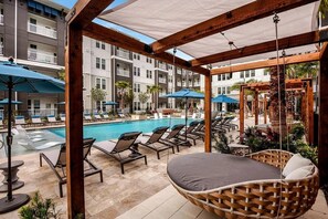 A poolside area with lounge chairs, umbrellas, and a wooden pergola. - Landing | Spectacular 2BD, Yoga Studio, Pool (St. Augustine)