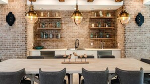 A modern kitchen with exposed brick walls, wooden beams, and pendant lighting. - Landing | Spectacular 2BD, Yoga Studio, Pool (St. Augustine)