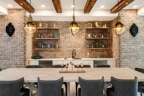 A modern kitchen with exposed brick walls, wooden beams, and pendant lighting. - Landing | Spectacular 2BD, Yoga Studio, Pool (St. Augustine)