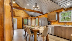 Un vaste espace dédié à la salle à manger, avec une table en bois dressée pour six personnes, entourée de chaises.