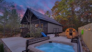 Un bain à remous, un chalet en bois et une structure cylindrique dans un jardin.