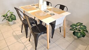 A dining table with four chairs, a clock on the wall, and two potted plants. - Loft céntrico | Kilómetro 0 | Fast WiFi | Moderno (Montevideo)