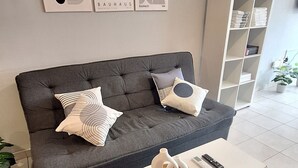 A modern living room with a grey sofa, two decorative pillows, a white coffee table, and a bookshelf. - Loft céntrico | Kilómetro 0 | Fast WiFi | Moderno (Montevideo)
