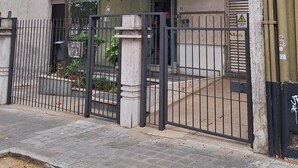 A multi-story building with a gated entrance, air conditioning units, and a palm tree in front. - Loft céntrico | Kilómetro 0 | Fast WiFi | Moderno (Montevideo)
