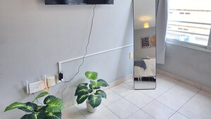 A modern room with a flat-screen TV mounted on the wall displaying 'NETFLIX', a potted plant, and a mirror reflecting the room. - Loft céntrico | Kilómetro 0 | Fast WiFi | Moderno (Montevideo)