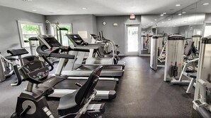 Une salle de sport équipée de tapis de course, de vélos elliptiques et d’appareils de musculation.