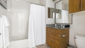 Une salle de bain avec une douche, des toilettes, un lavabo avec un miroir au-dessus et des meubles en bois.