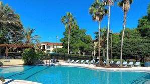 A swimming pool with lounge chairs and palm trees. - Landing | Spectacular 2BD, Tennis Court, Gym (Gainesville)