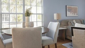 Een moderne woonkamer met een ronde tafel, twee fauteuils, een bank, een vloerlamp en een potplant.