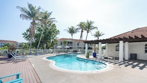 A swimming pool with a wooden deck, lounge chairs, and palm trees. - Landing | Chic 2BD, Gym, Clubhouse (North Port)