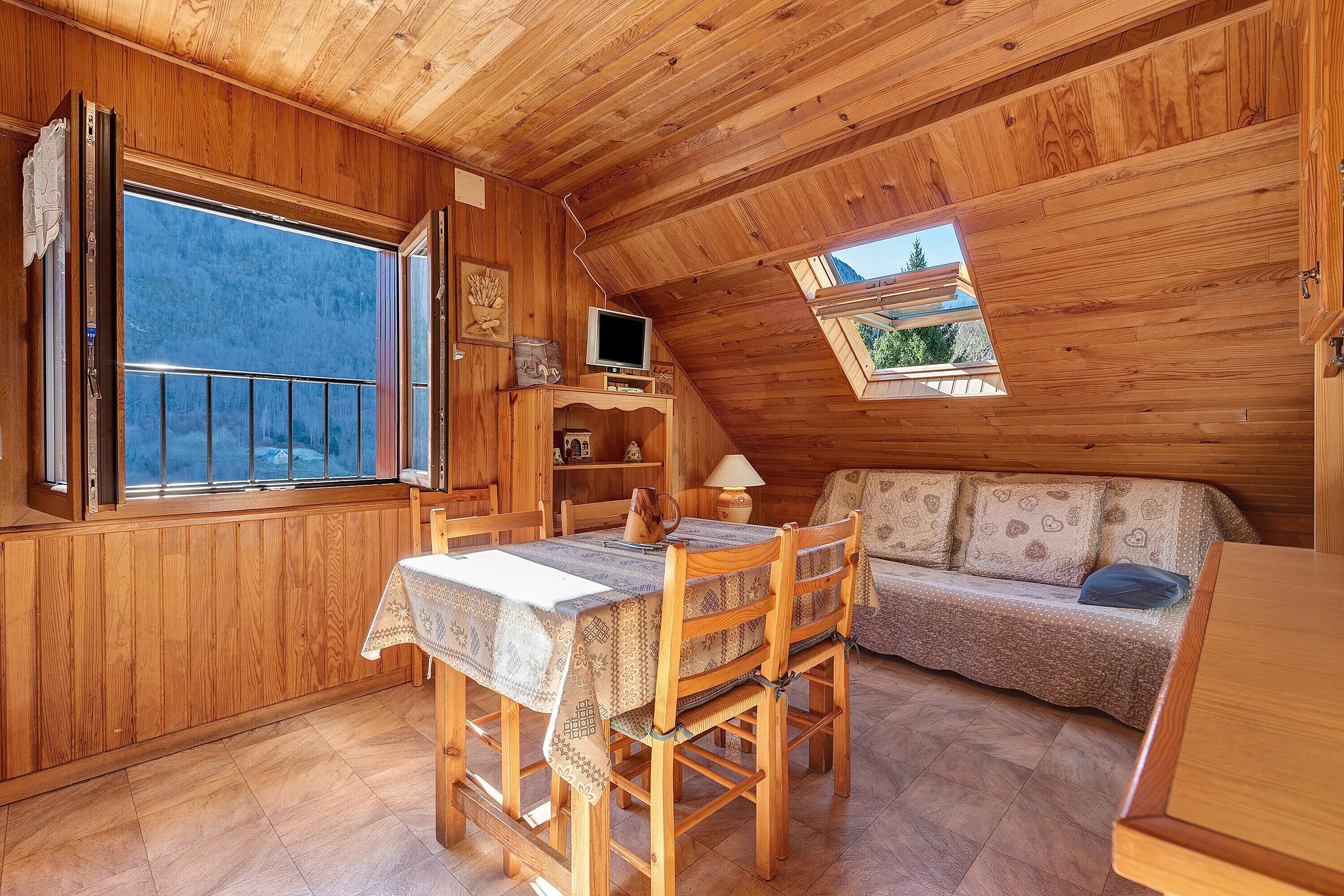 Un intérieur en bois comprenant une table à manger, des chaises, un canapé et un téléviseur.