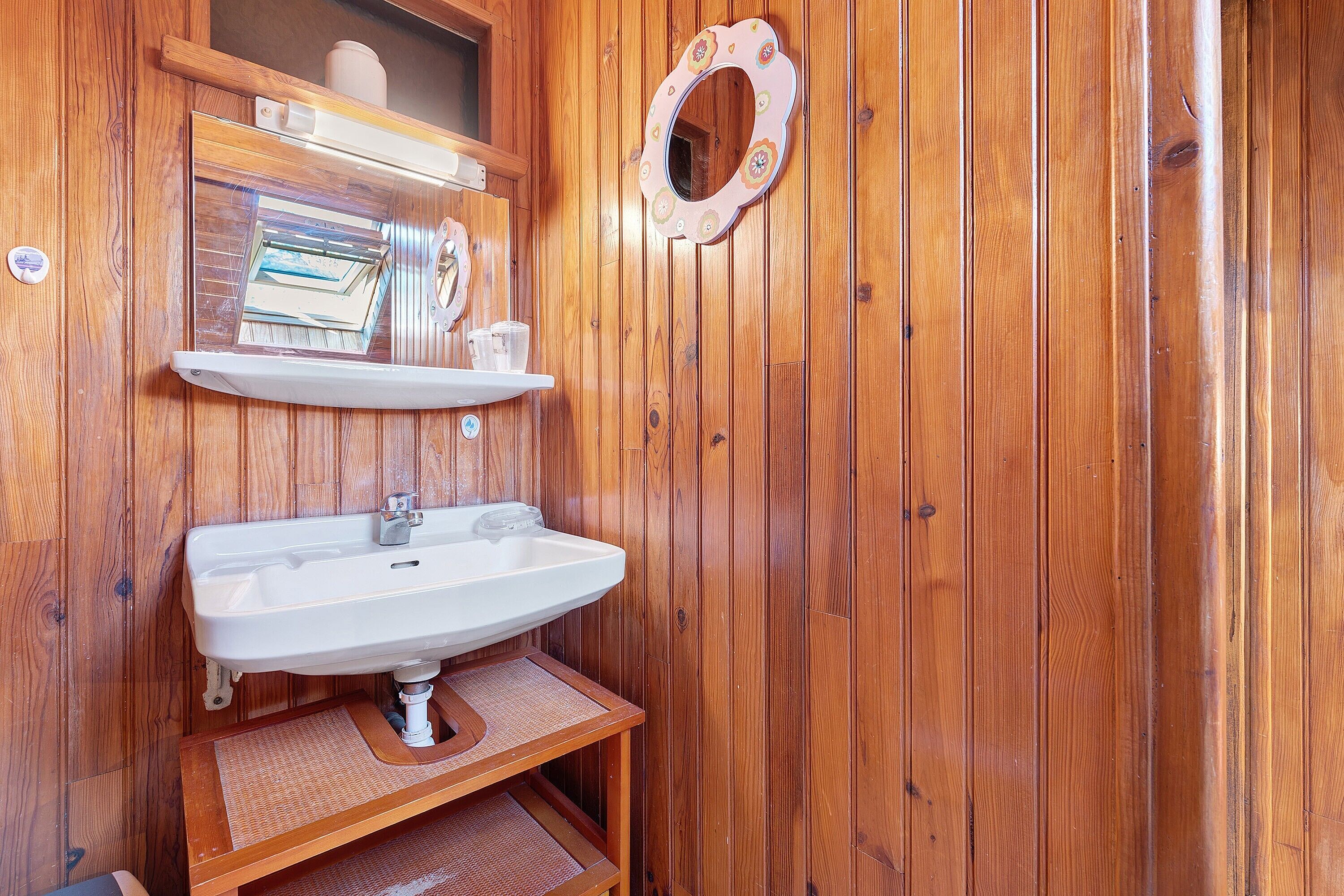 Ein Badezimmer aus Holz mit Waschbecken, Spiegel und Ablagefläche.