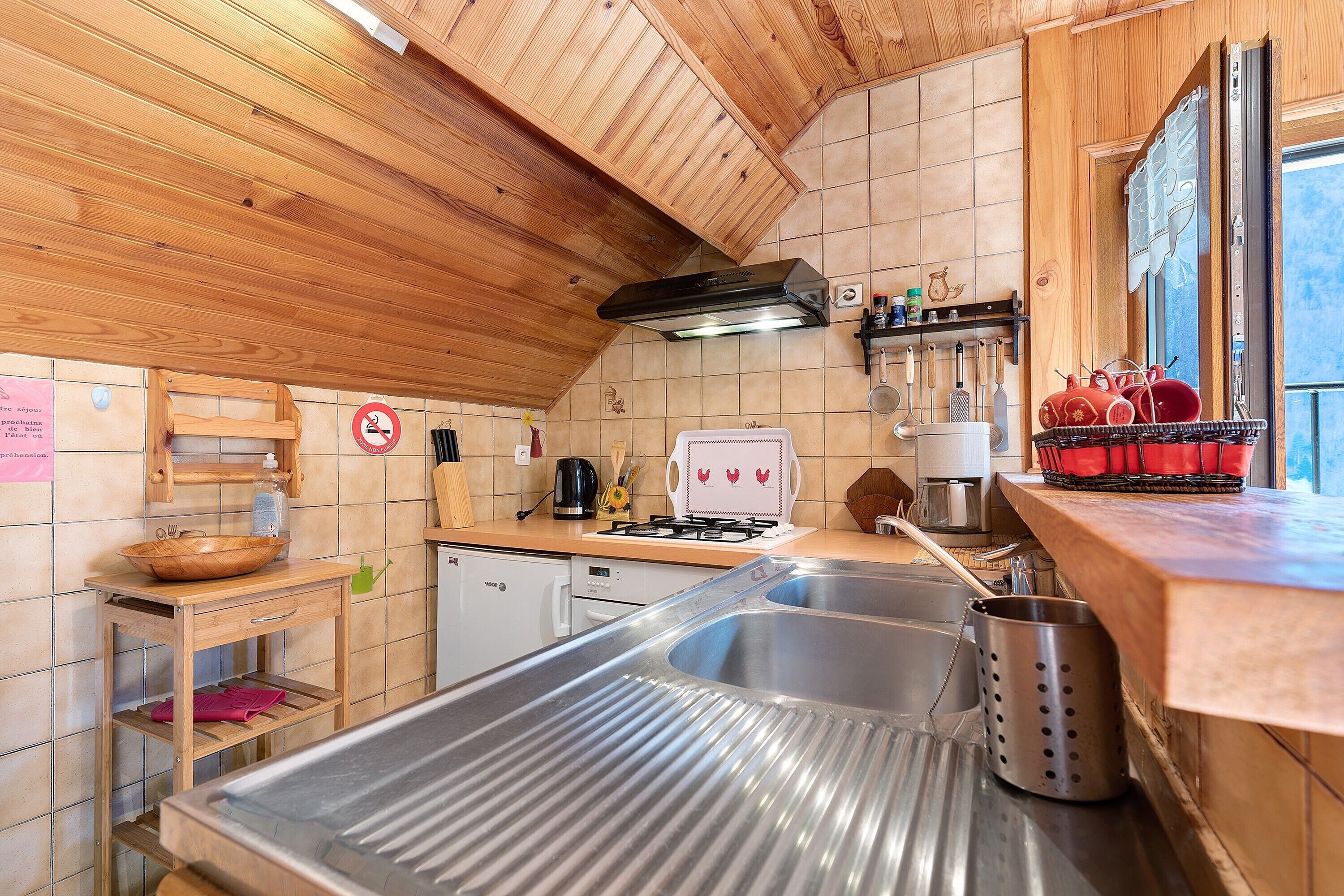 A kitchen with wooden ceiling, stainless steel sink, and a stove.