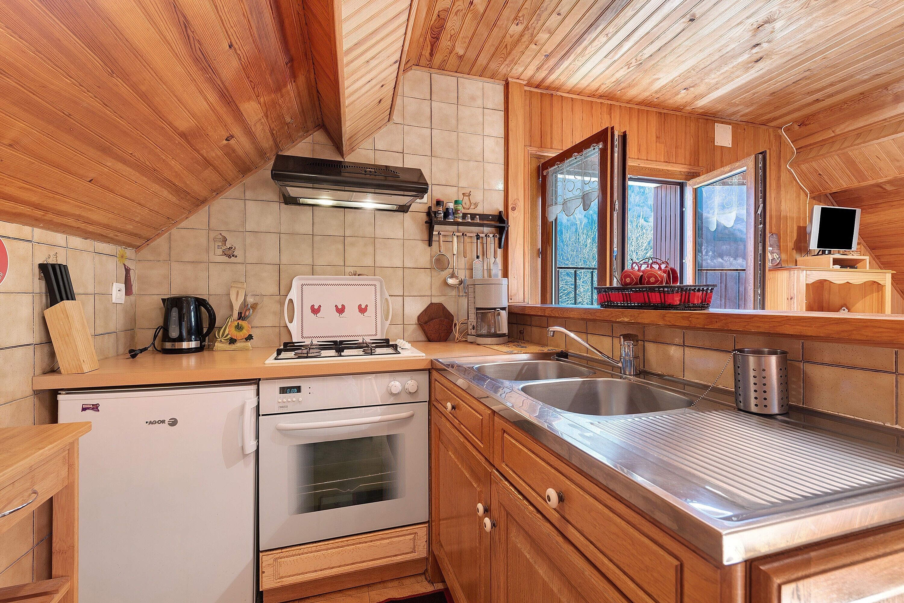 A compact kitchen with wooden cabinets, a built-in oven, a stove, and a sink.
