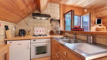A compact kitchen with wooden cabinets, a built-in oven, a stove, and a sink.