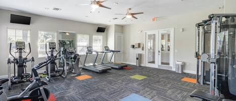 Ein Fitnessstudio mit Laufbändern, Crosstrainern, Fahrrädern und Gewichten.