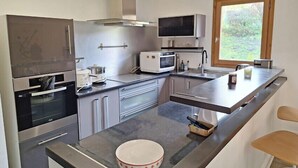 A modern kitchen with stainless steel appliances, a large window, and a bowl on the counter. - Modern apartment in the heart of Séez (Séez)
