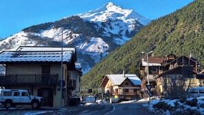 A mountain town with a snow-covered peak in the background, a road leading through the town, and buildings with visible balconies and signage. - Modern apartment in the heart of Séez (Séez)