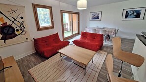 A modern living room with a sofa, a coffee table, and a dining area with a table and chairs. - Modern apartment in the heart of Séez (Séez)