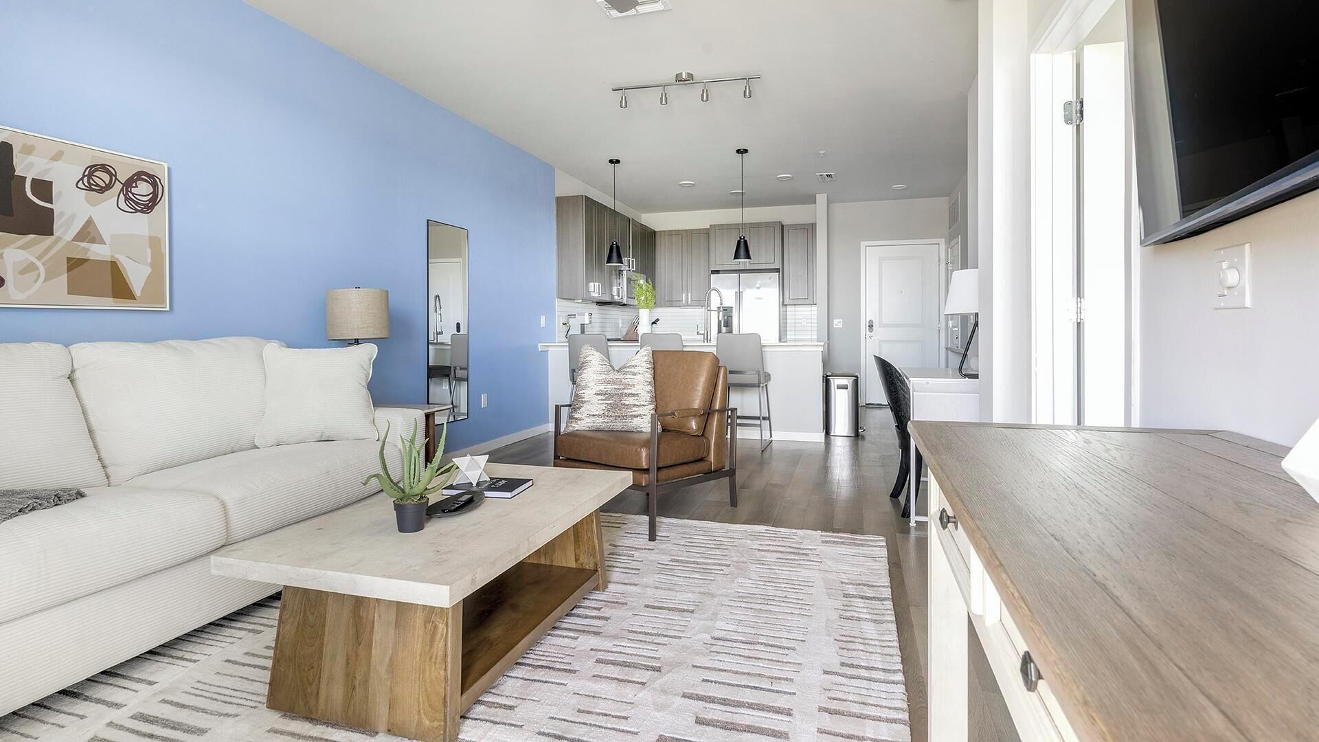 A modern living room with a sofa, coffee table, and a dining area with a table and chairs.