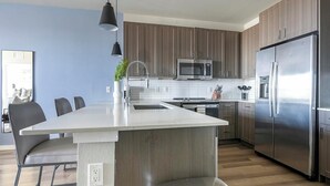 A modern kitchen with a central island, stainless steel appliances, and wooden cabinetry. - Landing | Beautiful 1BD, Clubhouse, Pool (Longboat Key)