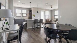 A modern kitchen with a dining area, featuring a central island, bar stools, and pendant lighting. - Landing | Beautiful 2BD, Game Room, Pool (Longboat Key)