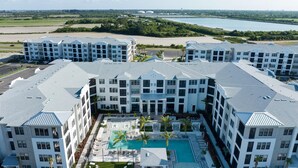 A modern hotel complex with multiple buildings, a central courtyard, and a swimming pool. - Landing | Beautiful 2BD, Game Room, Pool (Longboat Key)