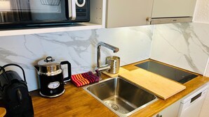 Une cuisine équipée d’un évier en acier inoxydable, d’une machine à café, d’une bouilloire et d’un four à micro-ondes.