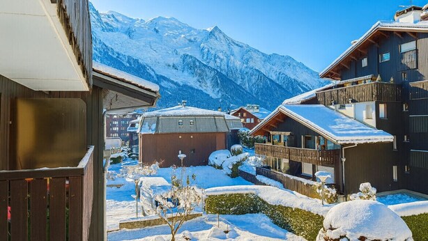 Un village de montagne enneigé, avec des bâtiments en bois et une vue dégagée sur les montagnes.