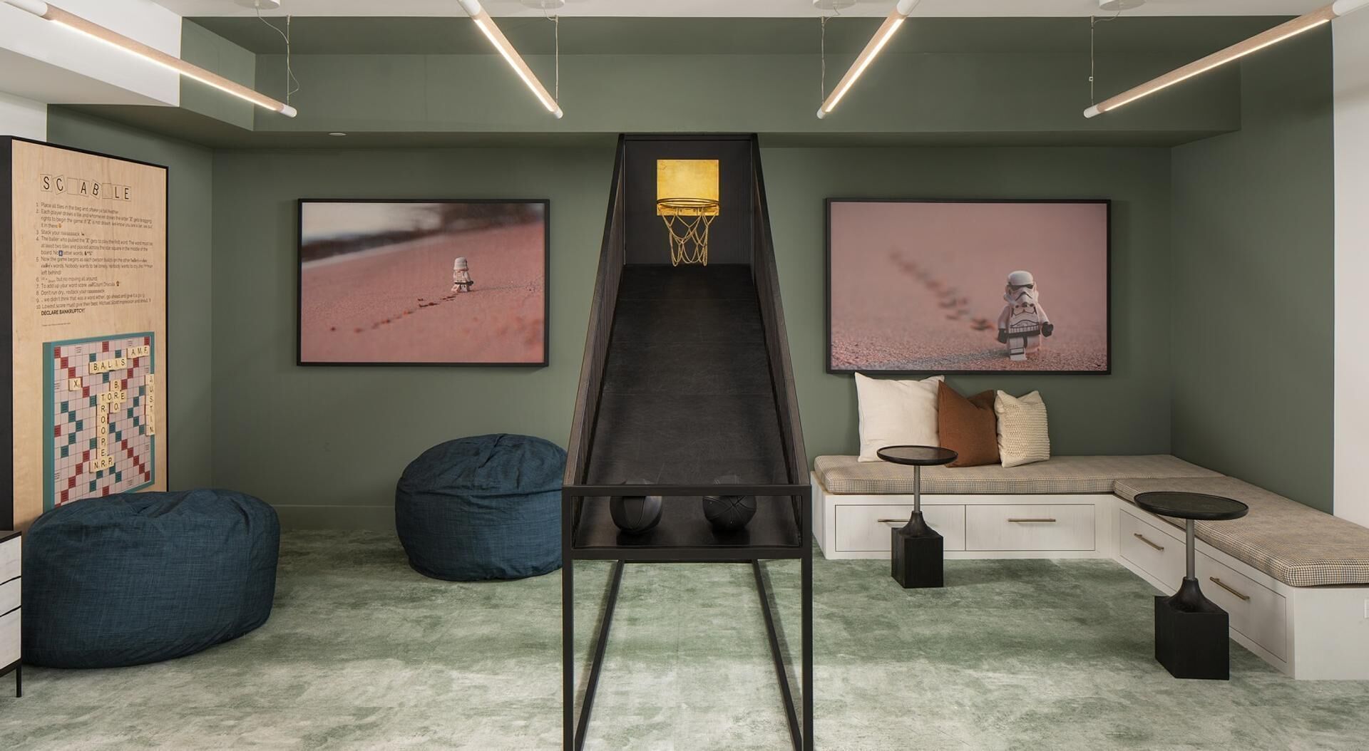 Une pièce comprenant un long bureau étroit, deux fauteuils en forme de poire, un banc avec des coussins et deux tableaux encadrés accrochés aux murs.