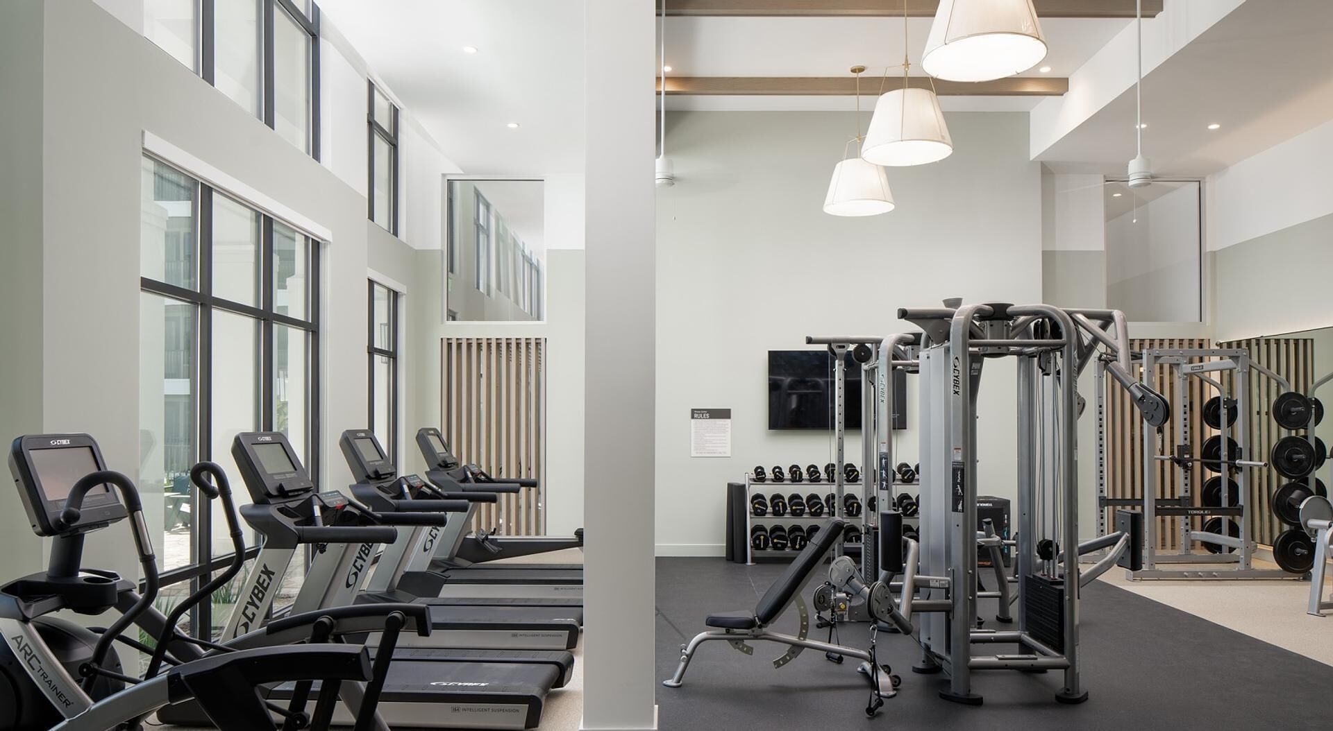 A gym with treadmills, weight machines, and a rack of dumbbells.