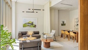 Uma sala de estar moderna com sofá, mesa de centro, área de jantar com cadeiras e obras de arte nas paredes.