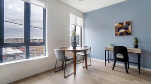 Ein modernes Wohnzimmer mit einem runden Esstisch, zwei Stühlen, einem kleinen Beistelltisch und einem Blumentopf.