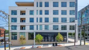 A multi-story building with a modern architectural design, featuring a large glass facade and a sign for 'GSBE Apartments'. - Landing | Amazing 2BD, Pool, Rooftop Lounge (Durham)