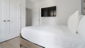 A bedroom with a bed, a television mounted on the wall, and a wardrobe.