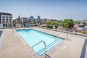 A rooftop pool with a metal railing, surrounded by a fence and a 'No Diving' sign.