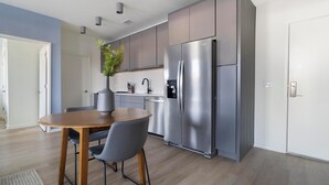 Une cuisine moderne avec un réfrigérateur en acier inoxydable, des armoires grises et une table à manger avec des chaises.