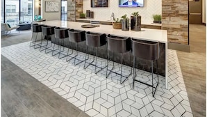 A modern kitchen with a long bar area, pendant lighting, and a stone backsplash. - Landing | Chic 1BD, Pool, Courtyard (Austin)