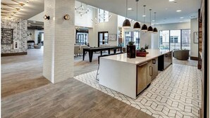 A spacious kitchen with a central island, pendant lighting, and a view of the dining area. - Landing | Chic 1BD, Pool, Courtyard (Austin)
