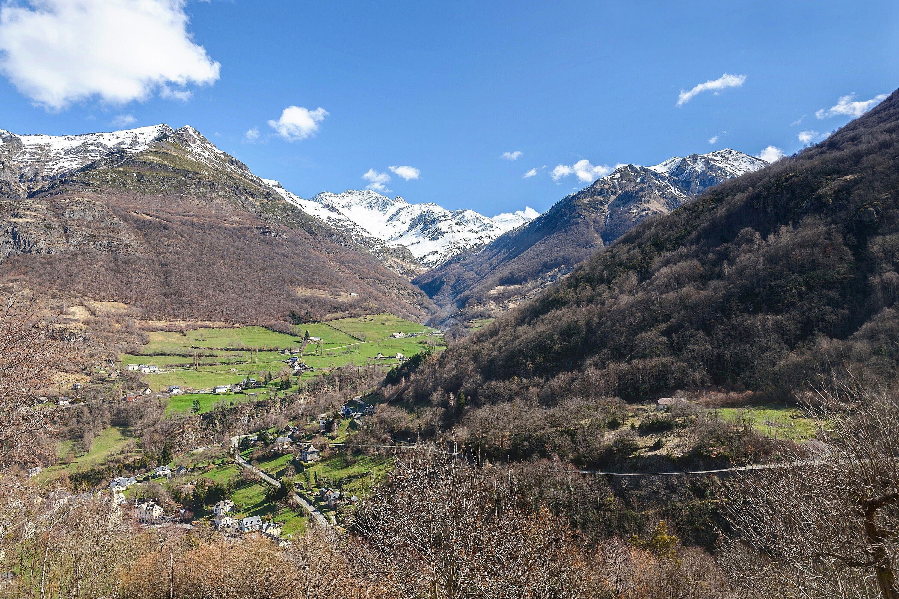 Eine gebirgige Landschaft mit einem Tal, Häusern und blauem Himmel.