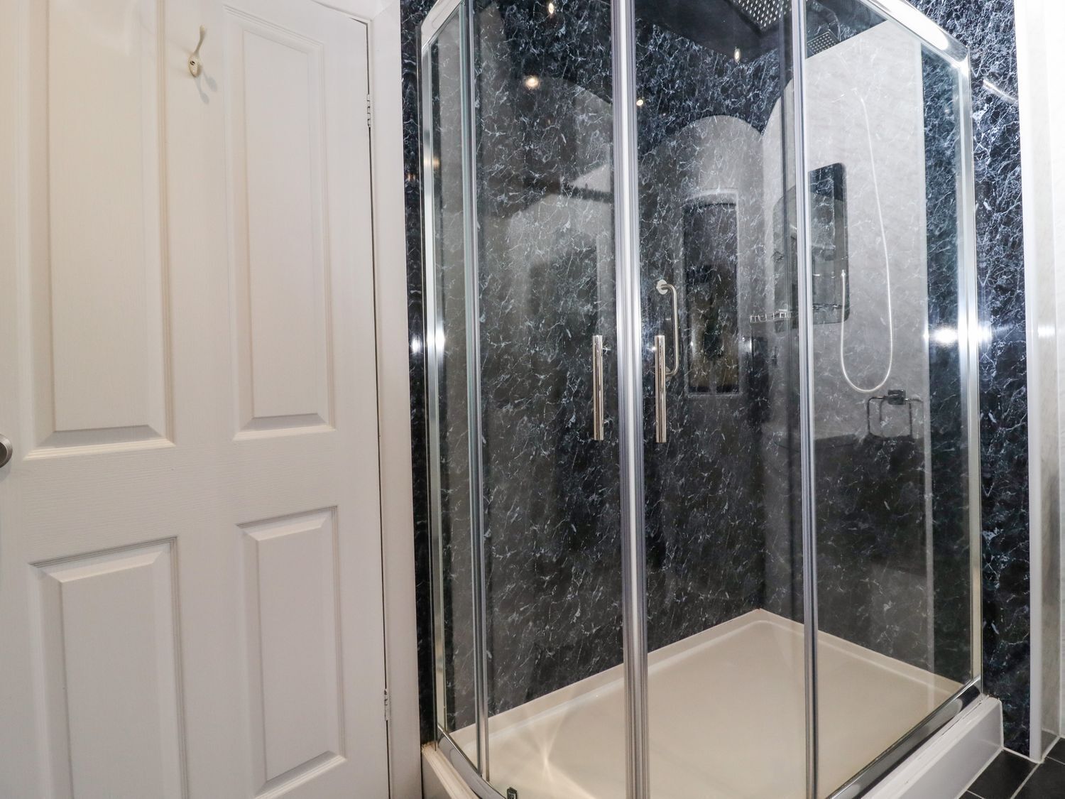 Une douche à l’italienne avec des portes en verre et un pare-splash en marbre.