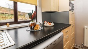 Eine Küche mit Fenster, einer Hahn-Dekoration, einer Glastheke mit Lebensmitteln und einem Teller mit Eiern.